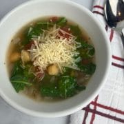 bowl of kale and chickpea soup topped with cheese