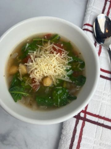 bowl of kale and chickpea soup topped with cheese