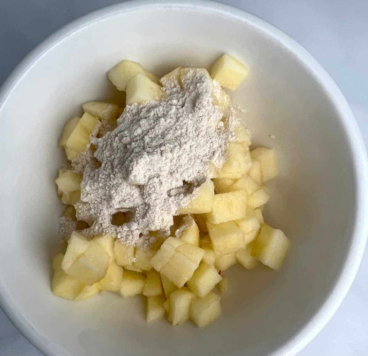 a spoonful of cake mix on top of chopped apples