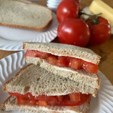 tomato sandwich in foreground with tomatos and bread in background