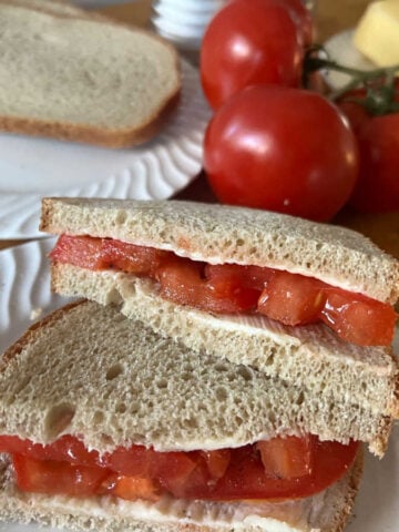tomato sandwich in foreground with tomatos and bread in background