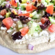 Greek seven layer dip with hummus, chopped tomatos, cucumbers, feta and olives