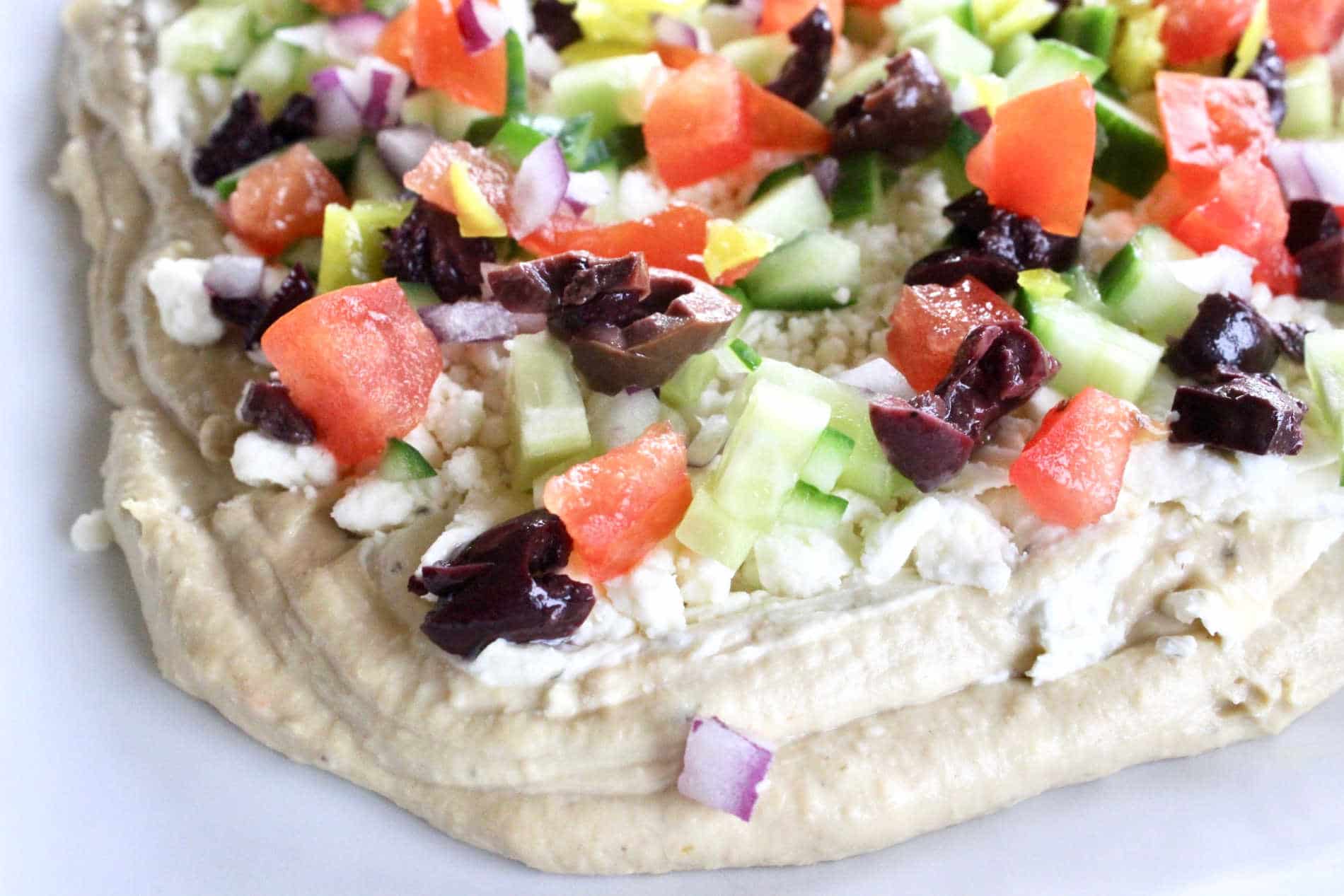 Greek dip with hummus, chopped tomatos, cucumbers, feta and olives
