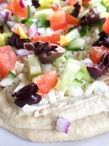 Greek seven layer dip with hummus, chopped tomatos, cucumbers, feta and olives