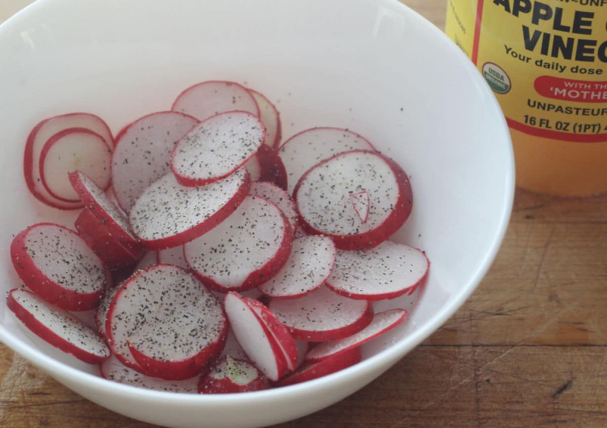 sliced radishes with salt and pepper in a white bowl