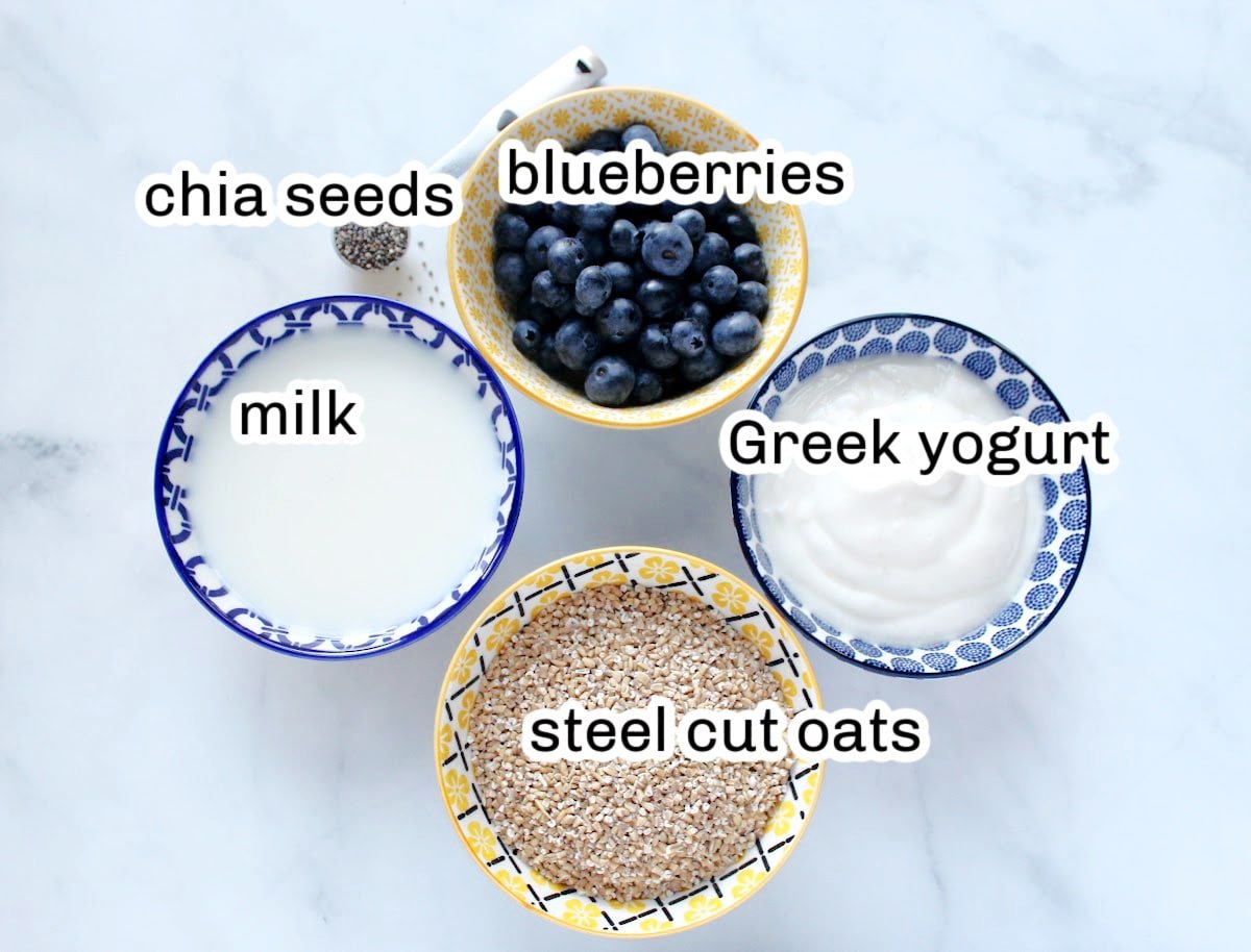 Overnight oats ingredients including steel cut oats, greeek yogurt, blueberries, milk and chia seeds.