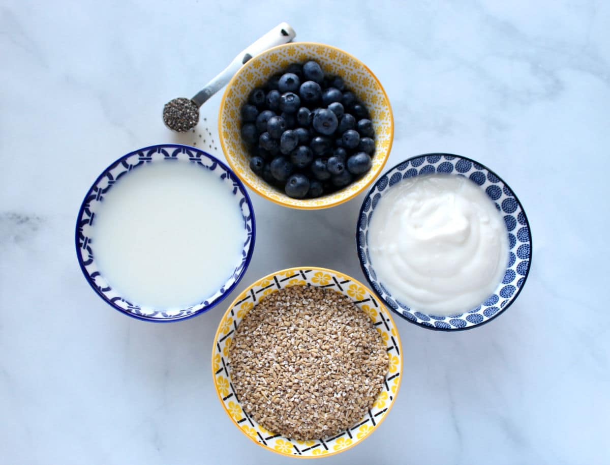 ingredients for overnight oats includes oatmeal, yogurt, milk, optional chea seeds and blueberries.