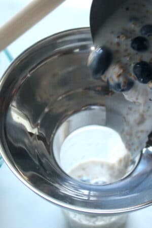 using a canning funnel to portion overnight oats.