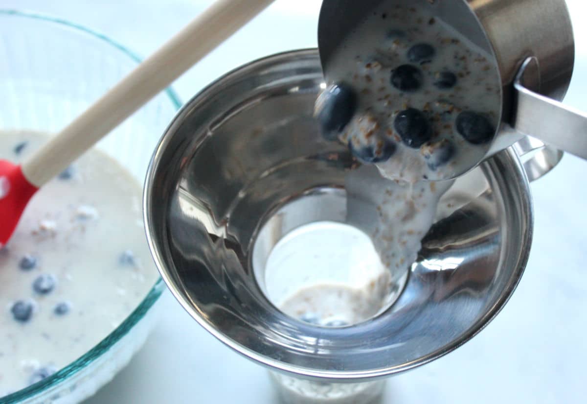 using a canning funnel to portion overnight oats.