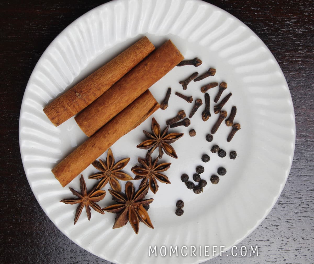 cinnamon sticks, whole anise, peppercorns and cloves on a white plate