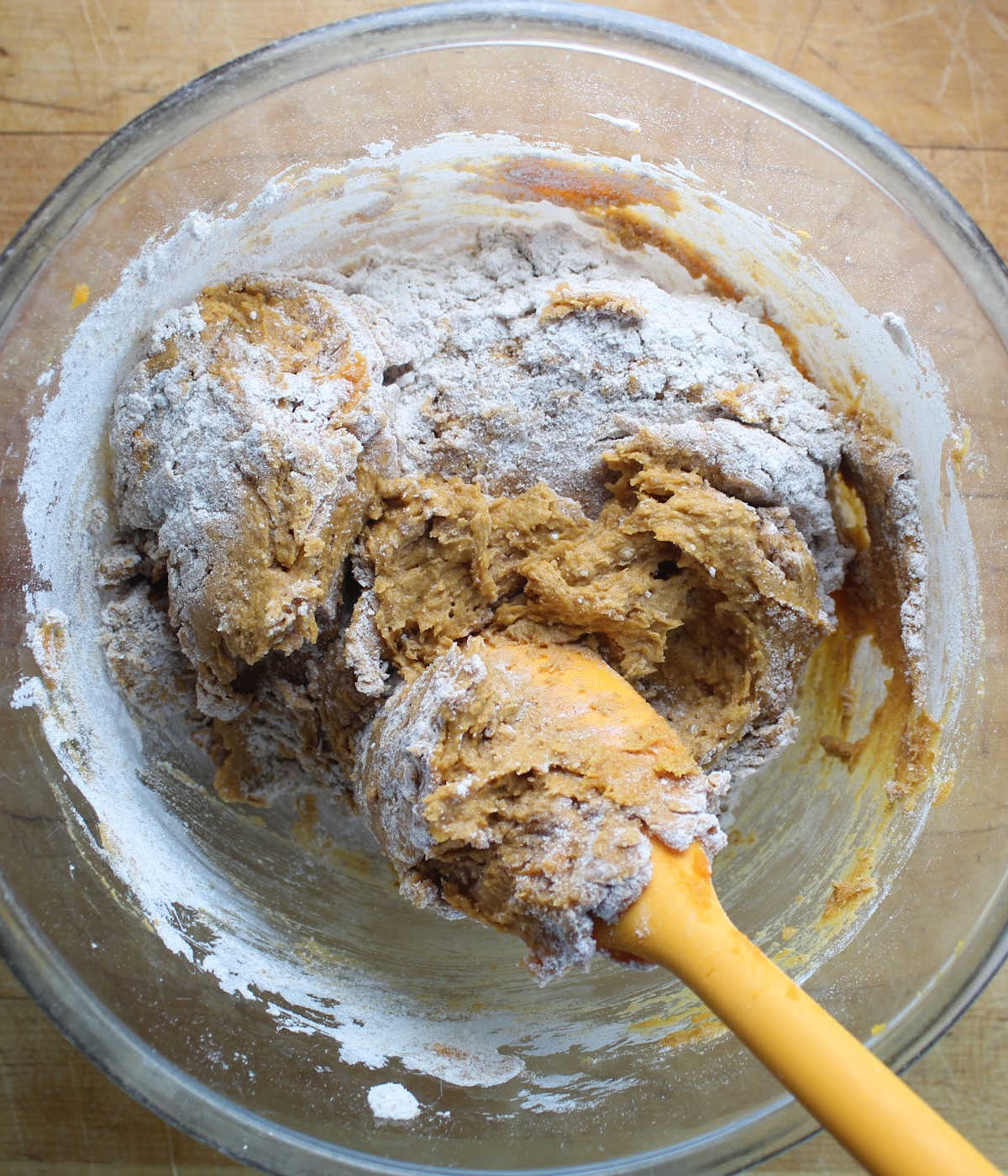 pumpkin batter being stirred with an orange spoon.