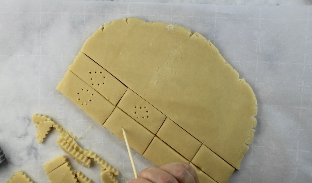 making a design on cut out shortbread cookies with wooden skewer