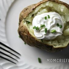 baked potato with sour cream and chives on a white plate
