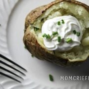 baked potato with sour cream and chives on a white plate