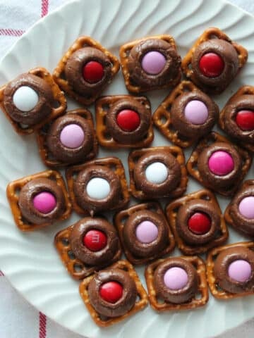 hershey kisses on pretzels with red, pink and white M & M's on top.