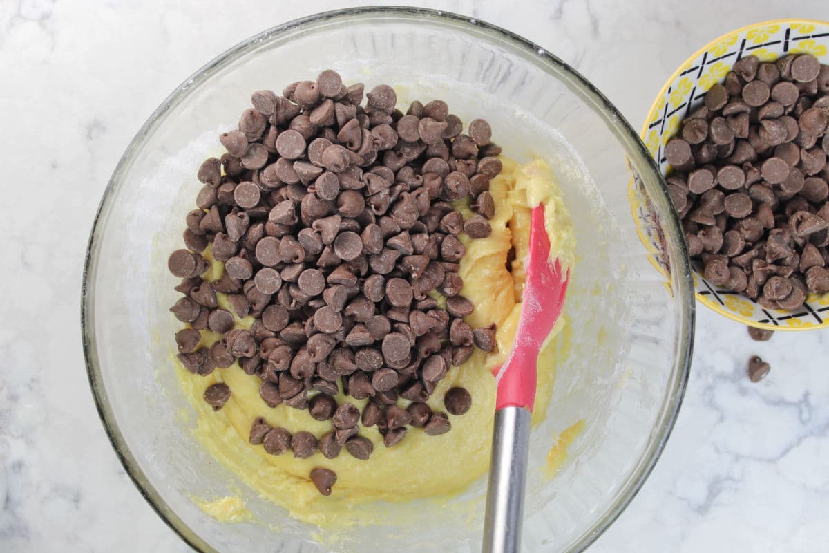 adding chocolate chips to cookie bar dough.