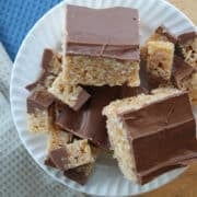 a plate with full sized scotcheroo cereal squares and small cut pieces.