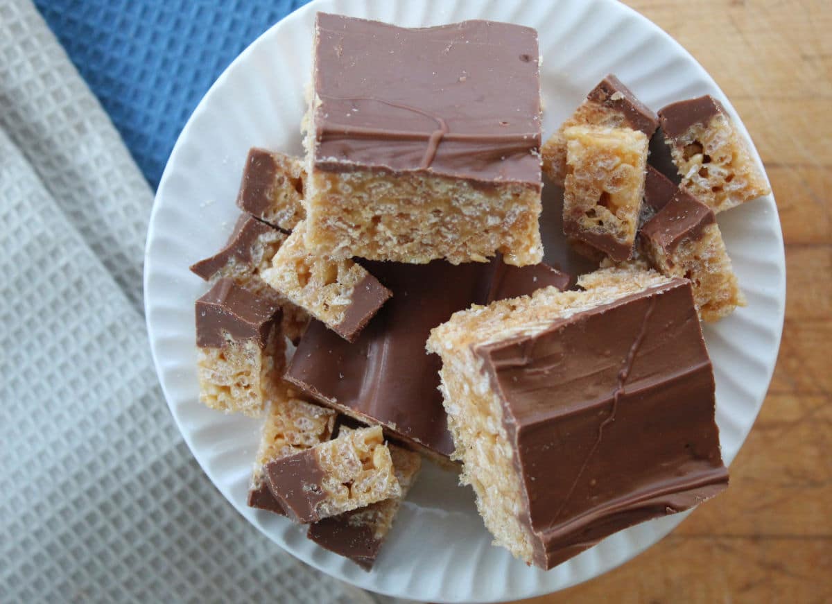 a plate with full sized scotcheroo cereal squares and small cut pieces.