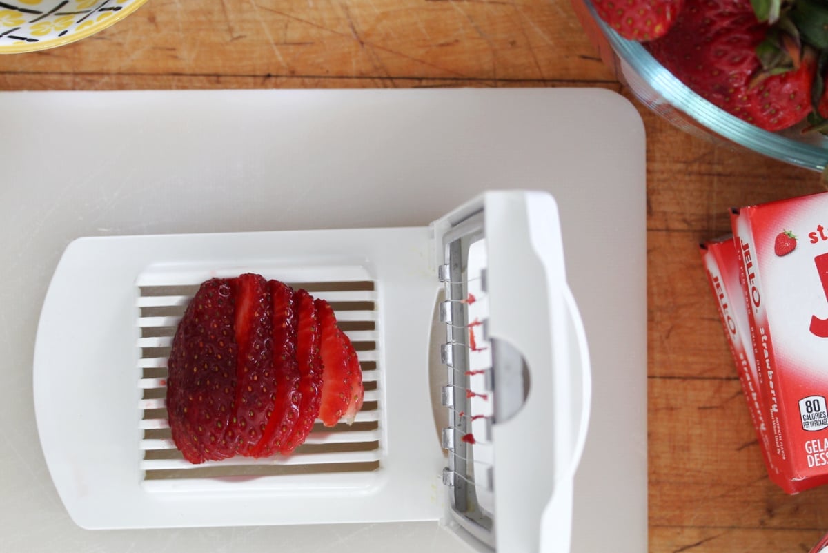 using an egg slicer to cut up strawberries.