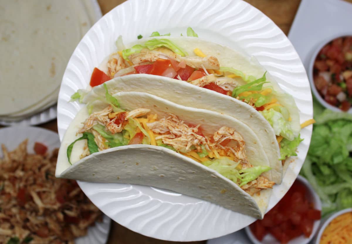 two shredded chicken tacos on a white plate.