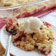 a serving of strawberry dump cake with vanilla ice cream on a white plate.