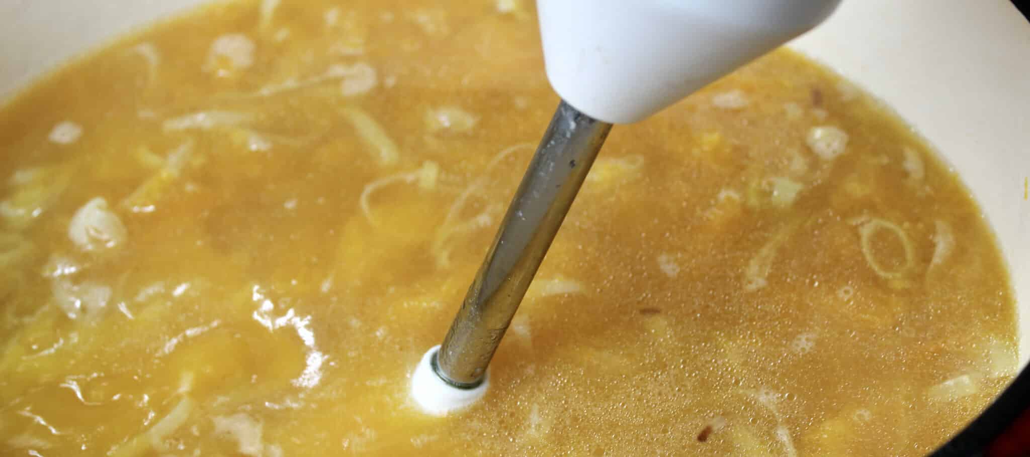 butternut squash soup being blended with imersion blender