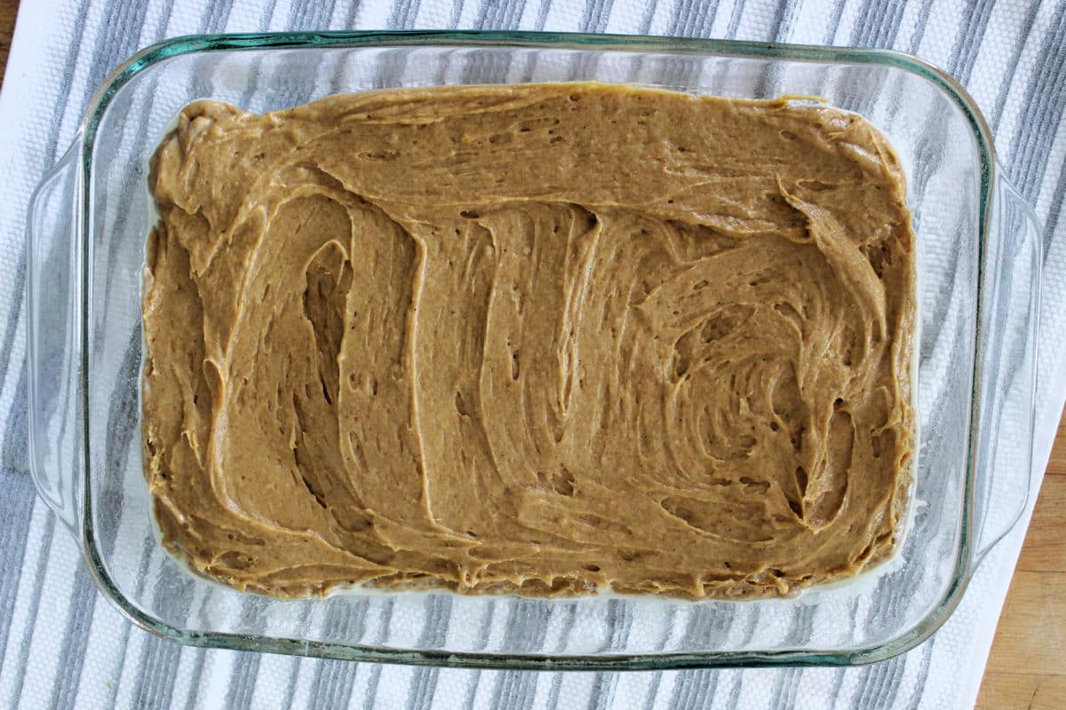 pumpkin dump cake batter is dumped into baking dish and spread out evenly.