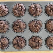 A dozen freshly baked chocolate chip pumpkin muffins in a muffin tin.