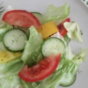 Closeup of vegetable salad with dill dressing drizzled over it.