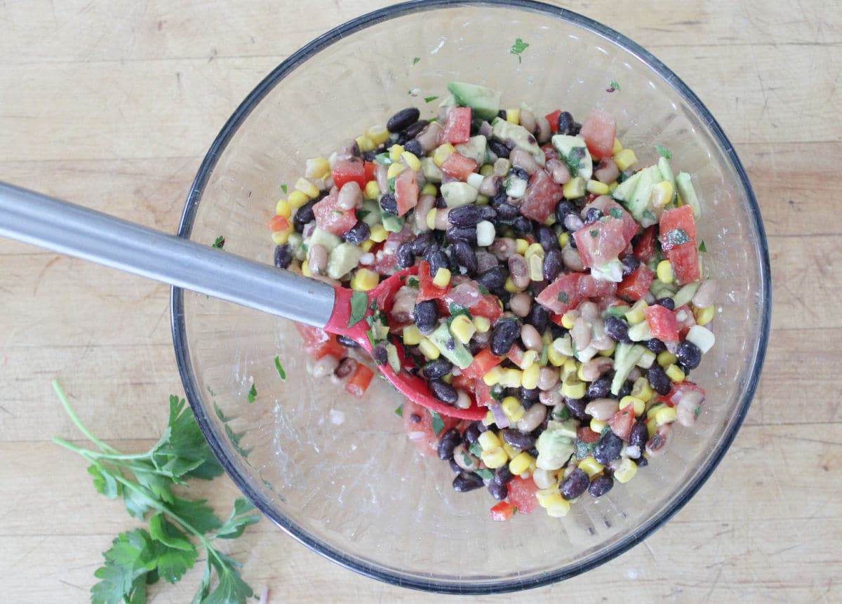 All ingredients in cowboy caviar being stirred together in a glass bowl.