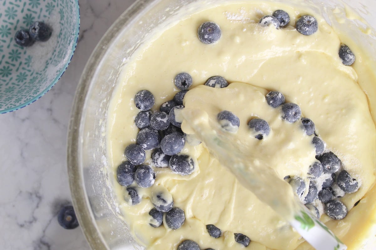 folding in blueberries into the muffin batter