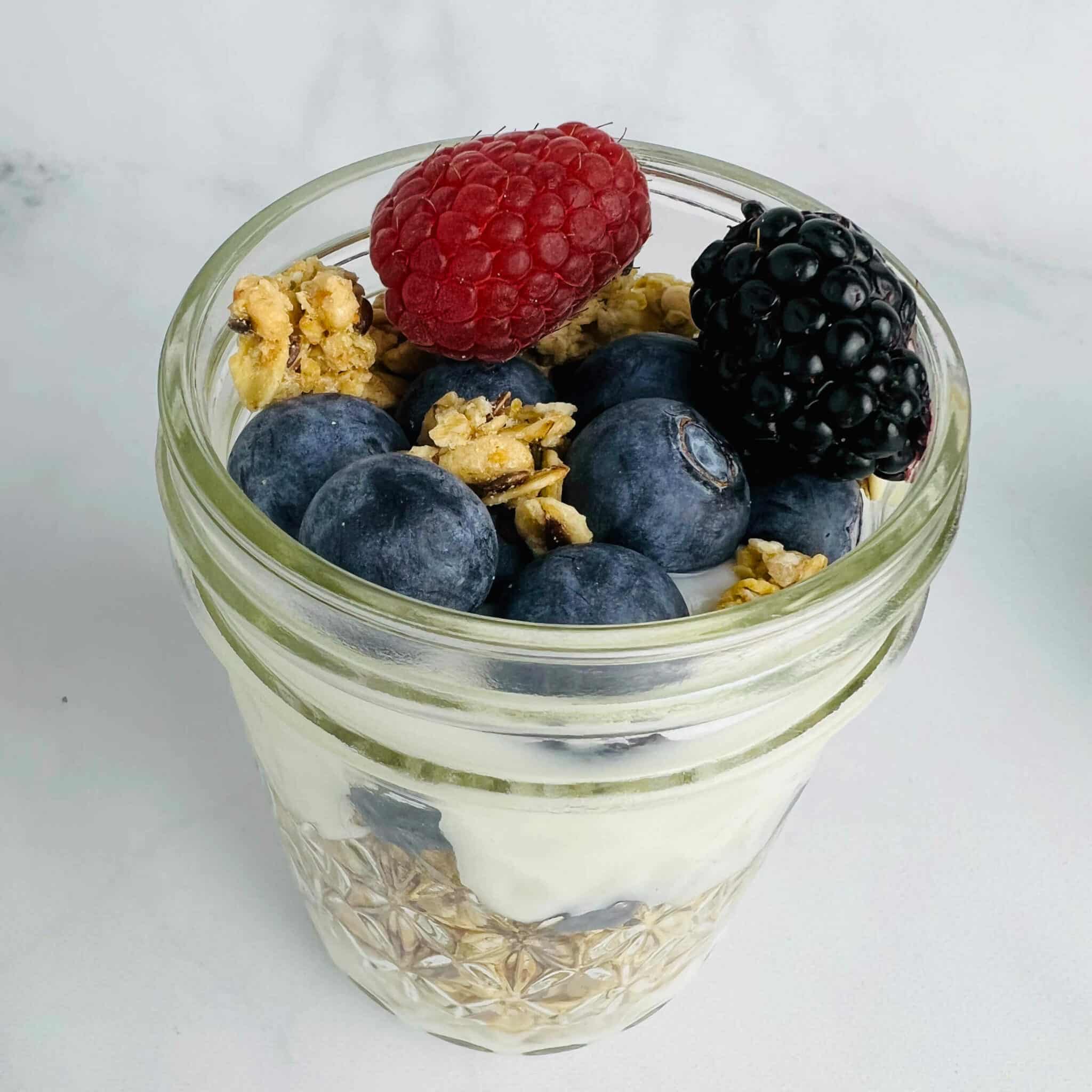 large yogurt and granola parfait in a mason jar with berries