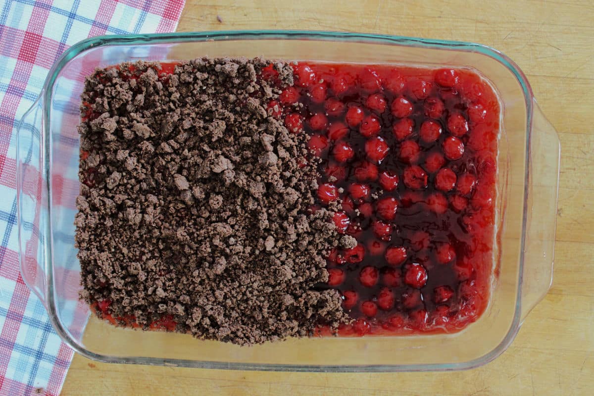 A baking dish with pie cherries as the bottom layer and a chocolate cake mix layer on top.