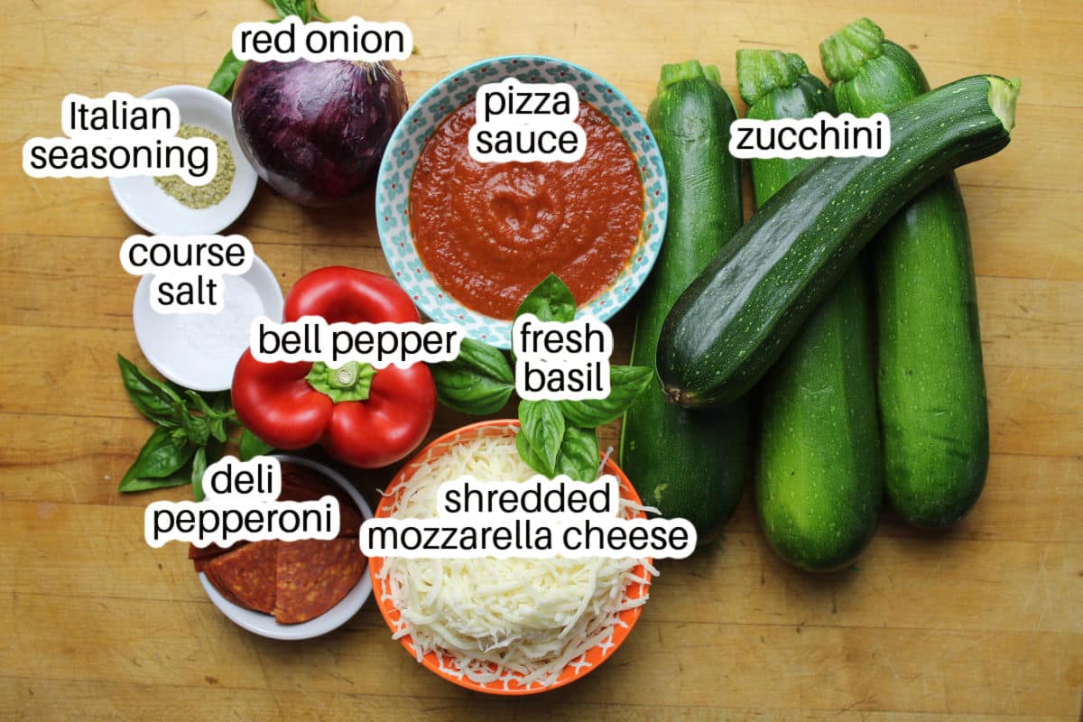 ingredients for pizza boats made on zucchini halves.  Includes zucchini, pizza sauce, seasonings, bell pepper, onionshredded cheese and fresh basil