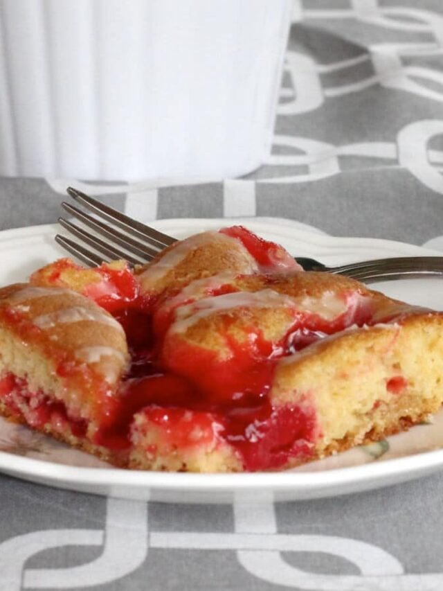 cherry pie square on a table with a gray table cloth and a cup of tea.