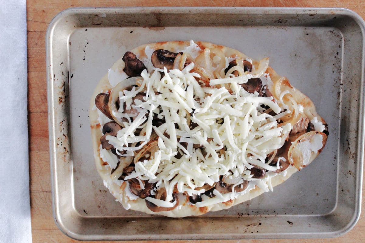 add sautéed mushrooms and onions onto naan bread.   Sprinkle mozzarella cheese on top. 