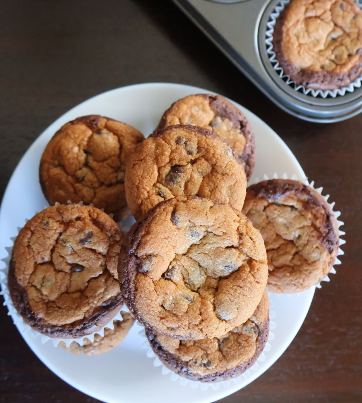 Brookies on a plate with a muffin tin with brookies still in it.