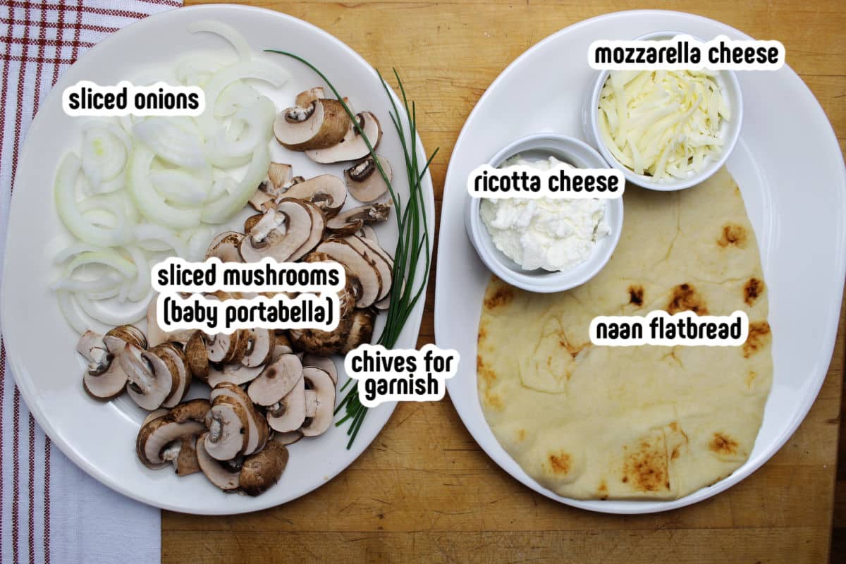 Ingredients for onion and mushroom naan pizza.  Includes naan bread, sliced mushrooms, sliced onions, ricotta cheese and mozarella shredded cheese.