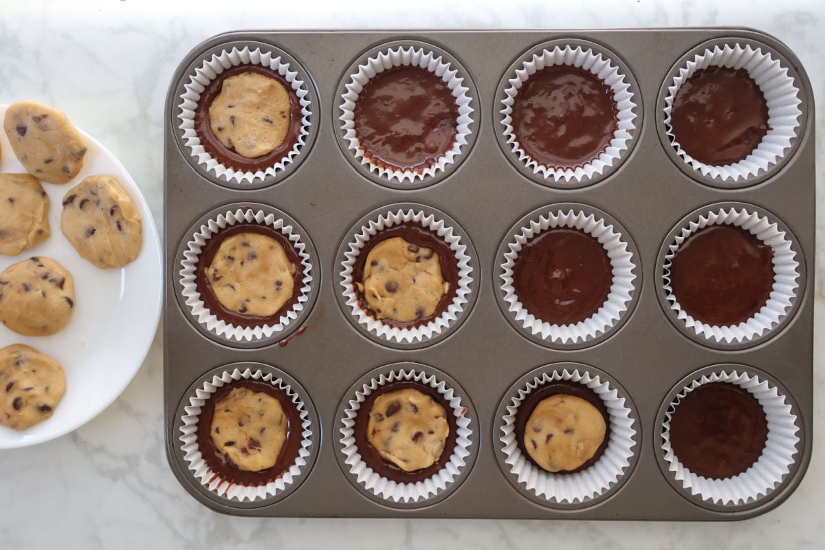 Placing a cookie dough disk on top of a layer of brownie batter.