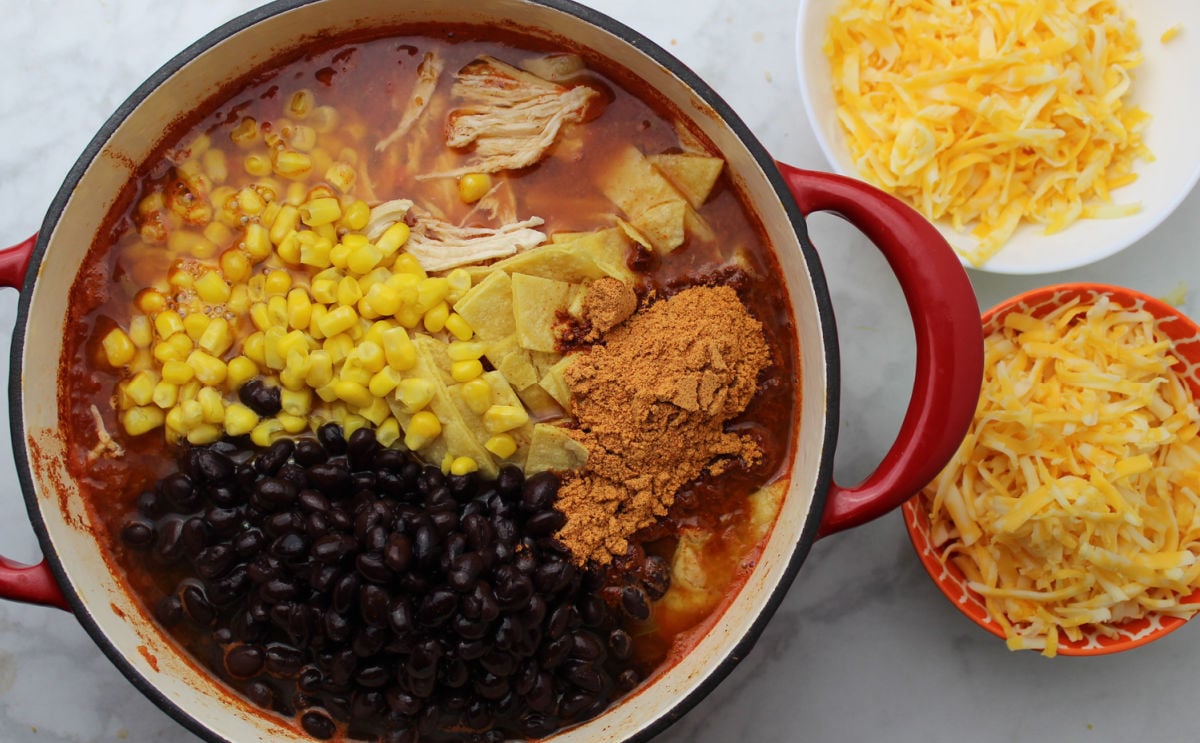 black beans, corn, cut up tortillas, shredded chicken and taco seasoning is in a red pot.