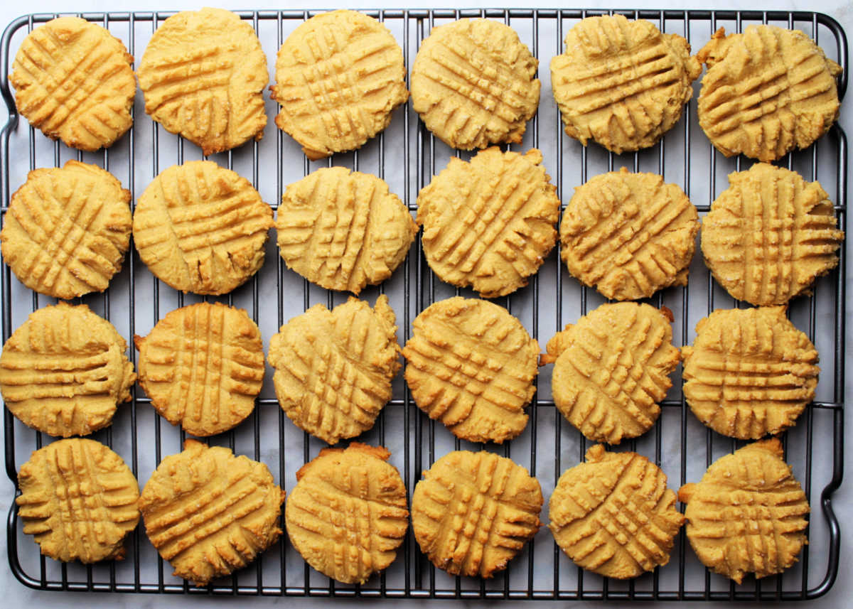 A batch of cake mix peanut butter cookies cooling on a cookie rack. Traditional criss cross markings are on the cookies.