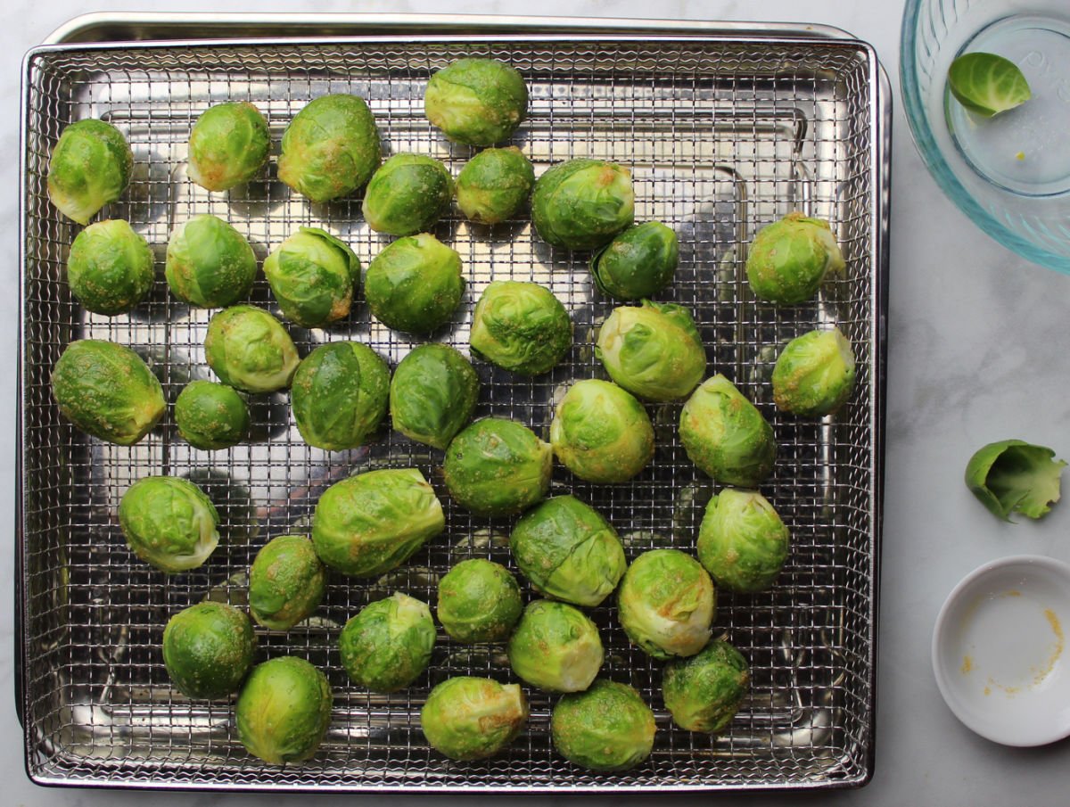 Brussels sprouts spread out on air fryer rack.