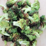 A pile of oven roasted broccoli with a slight char on the vegetable.