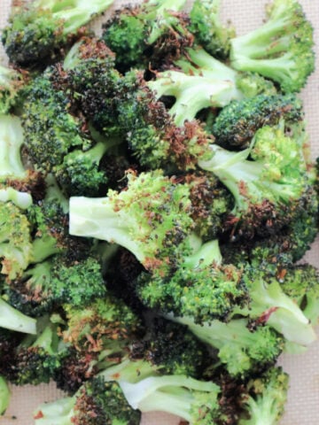 A pile of oven roasted broccoli with a slight char on the vegetable.