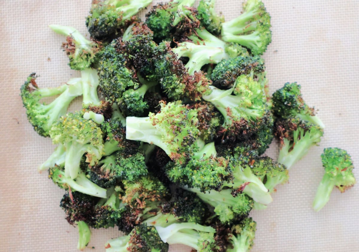 A pile of oven roasted broccoli with a slight char on the vegetable.