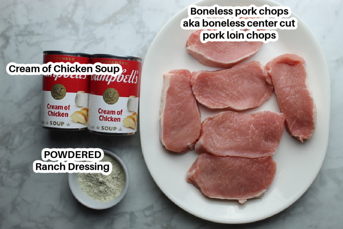 Boneless pork chops on a plate, two cans of cream of chicken soup and powdered ranch dressing mix.