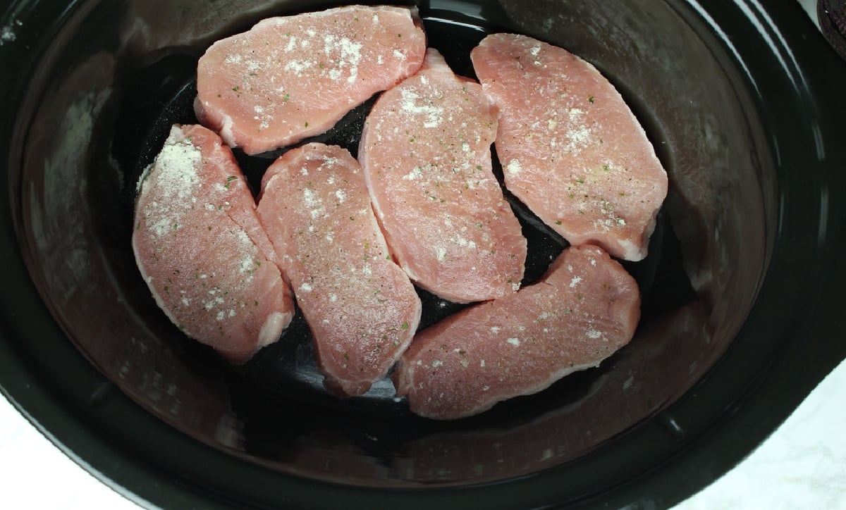 6 pork chops in the bottom of a black crock pot liner.
