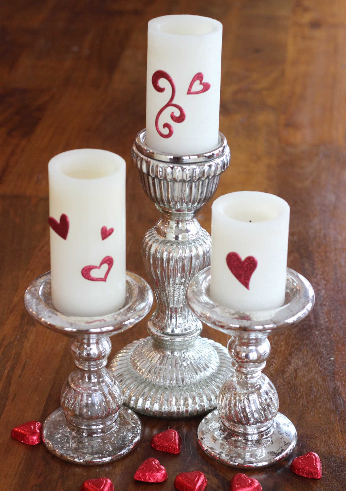 White candles with red heart stickers on them for Valentine's Day decor.
