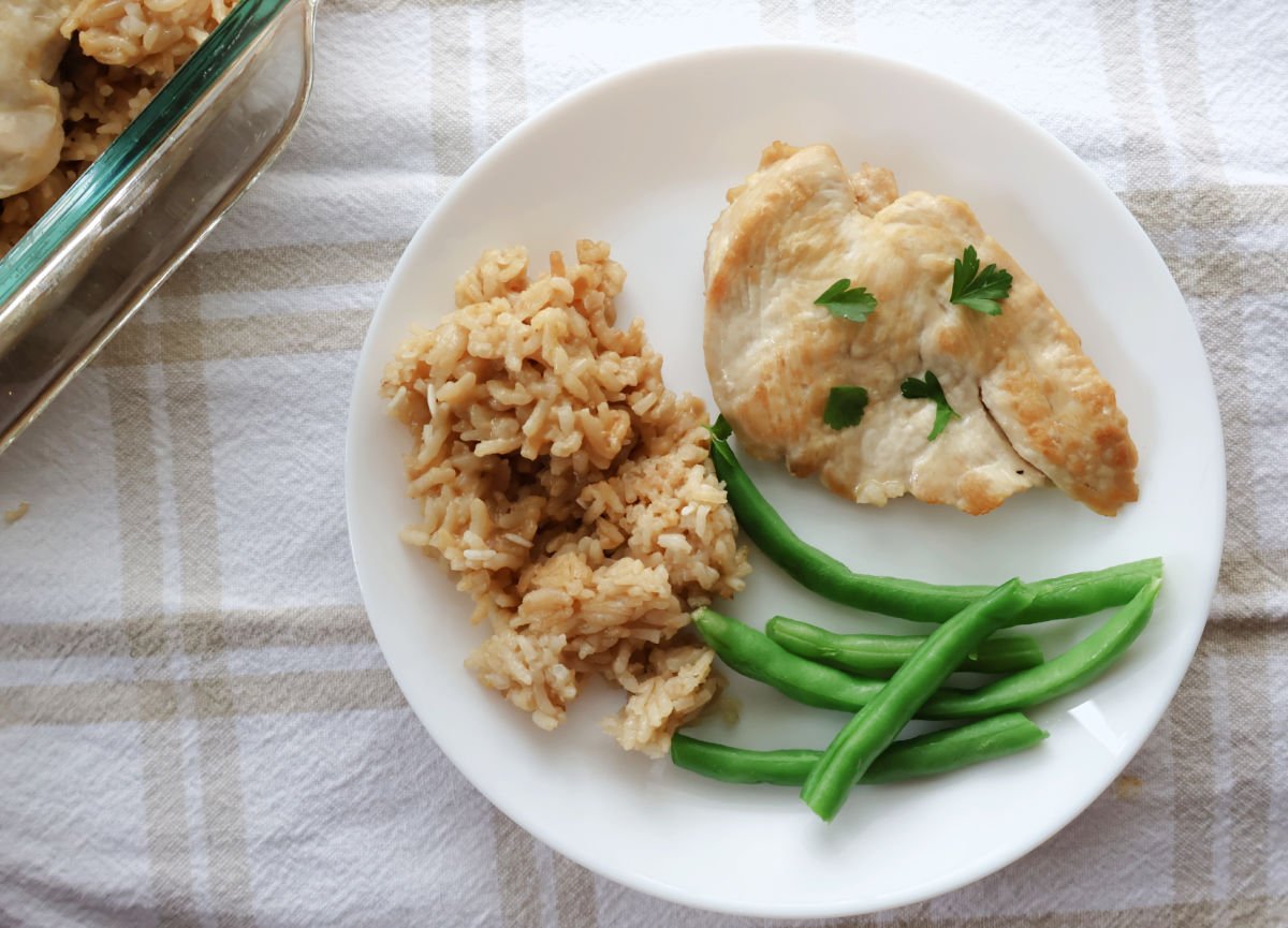 No peek chicken breast serves with fluffy seasoned rice and green beans on a white plate.