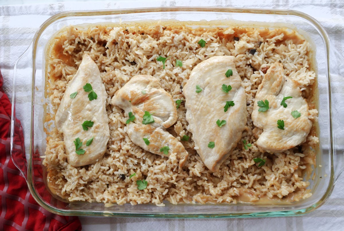 Chicken breasts on top of cooked rice that has been flavored with soup and soup stock.